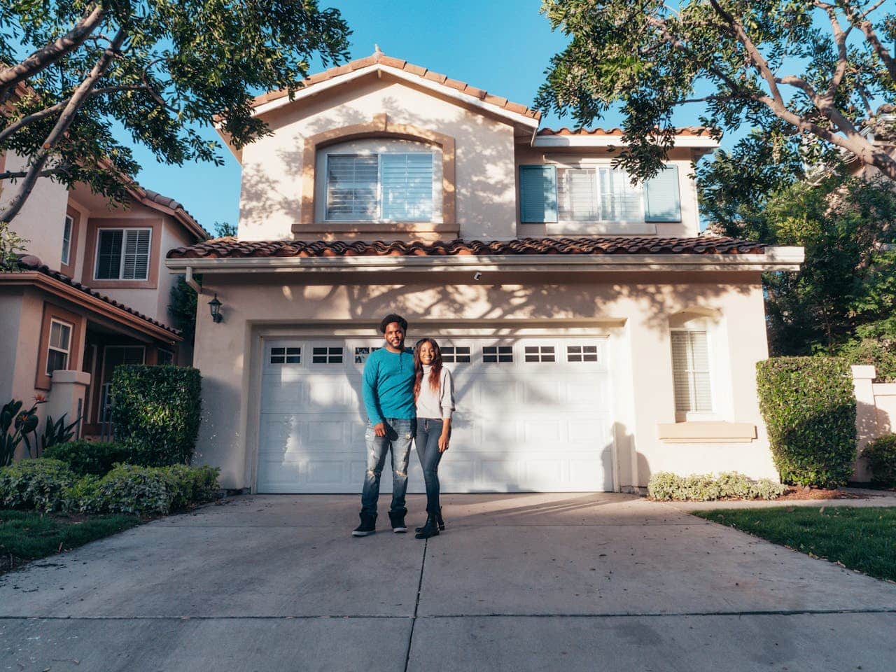 Couple standing in front of their new home, showcasing the benefits of Contract for Deed agreements in real estate transactions.