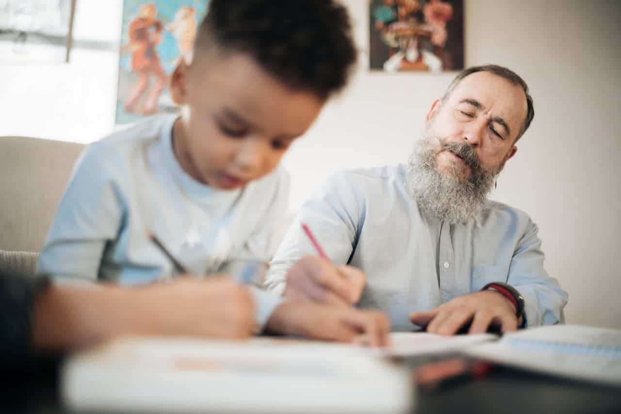 Man and child engaged in drawing together, illustrating family interaction and learning, relevant to real estate discussions about land contracts and home ownership.