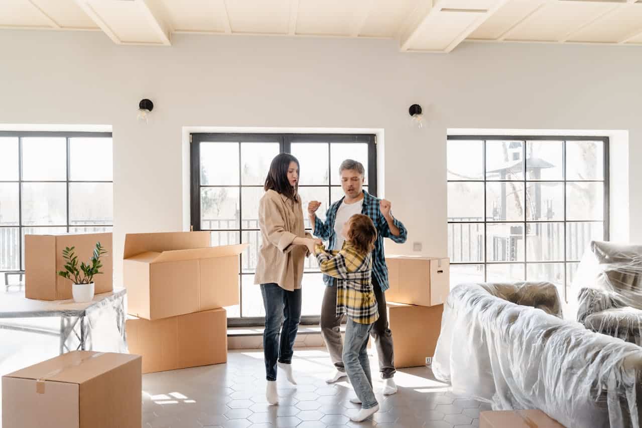 Family celebrating in a new home surrounded by moving boxes, illustrating the joy of homeownership through flexible financing options like contract for deed.