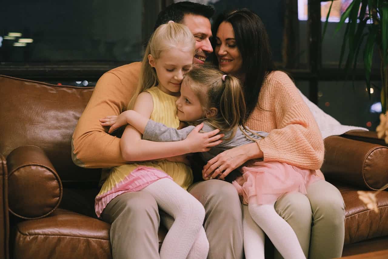 Family of four embracing on a couch, highlighting the warmth of home, relevant to discussions on balloon mortgages and family stability in home financing.