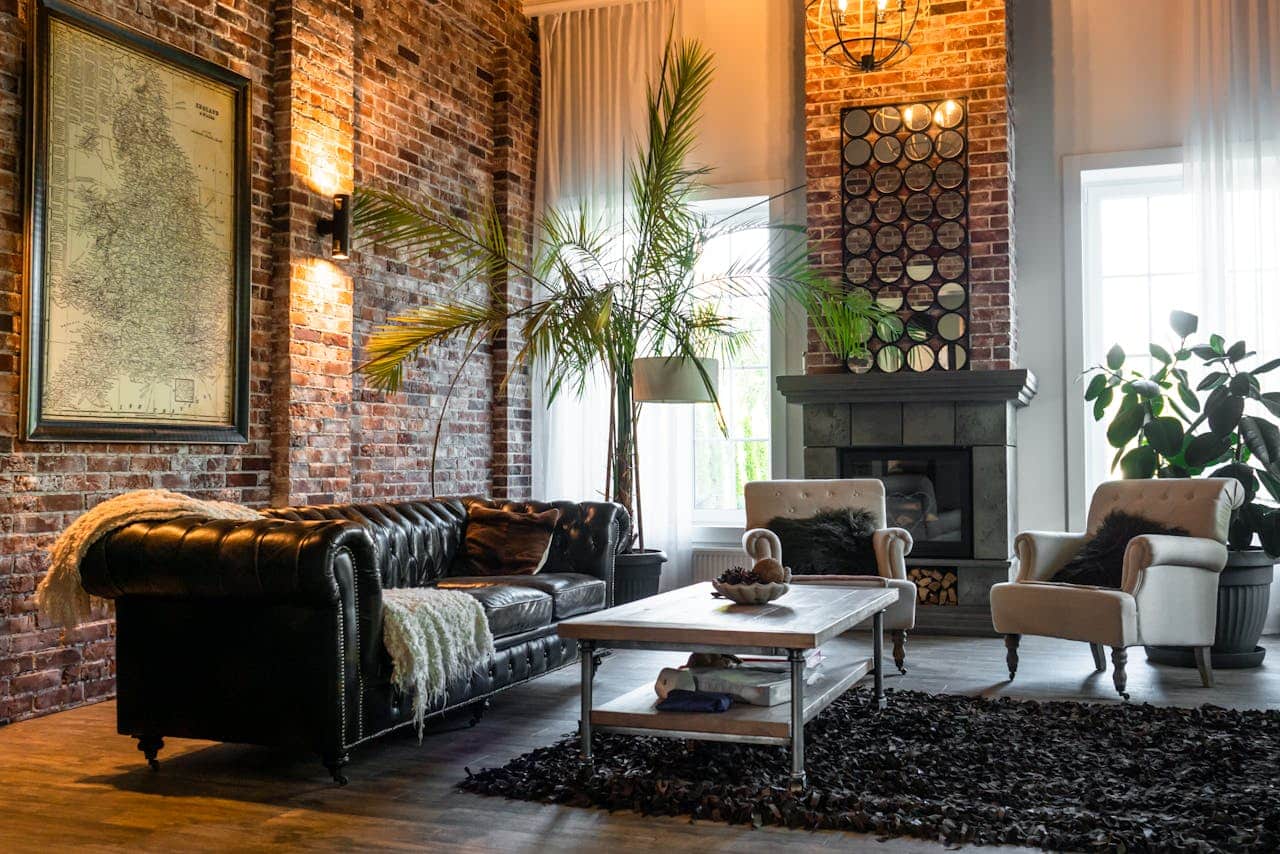 Cozy living room with a black leather sofa, a wooden coffee table, a decorative rug, and large windows, featuring a brick wall and indoor plants, reflecting a welcoming atmosphere for potential homebuyers with poor credit.