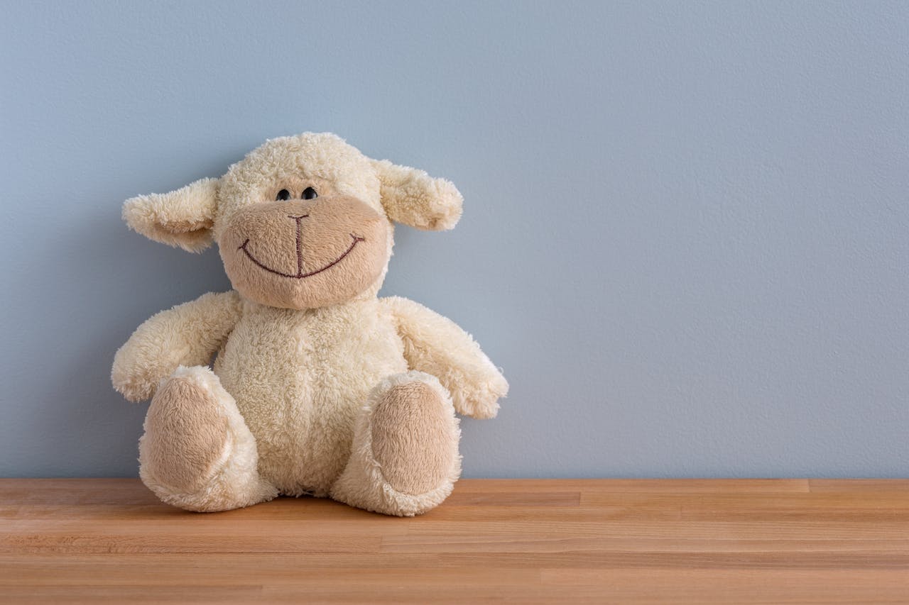 Teddy bear-like plush sheep sitting on a wooden surface against a light blue wall, symbolizing comfort and security in financial planning.