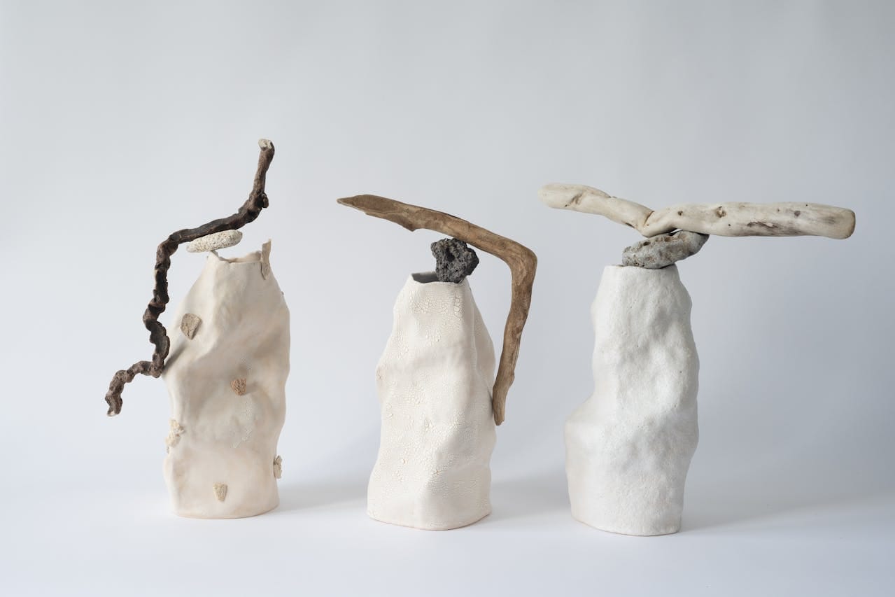 Three abstract sculptures made from textured white ceramic and natural driftwood, symbolizing stability and balance, representing themes of homeownership and financial security in the context of refinancing a Contract for Deed.
